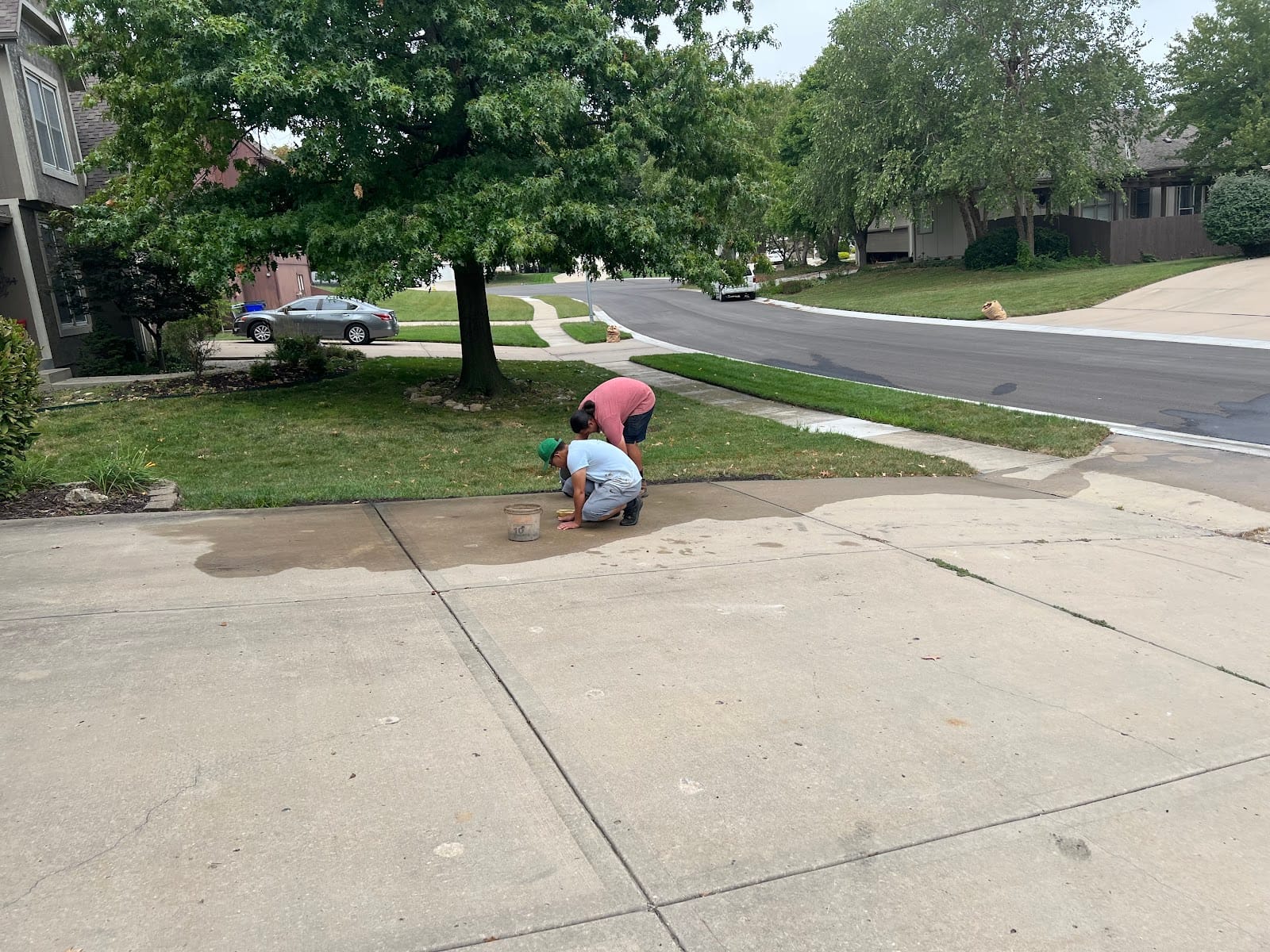An American Mudjacking technician leveling a residential concrete driveway in a Kansas City neighborhood